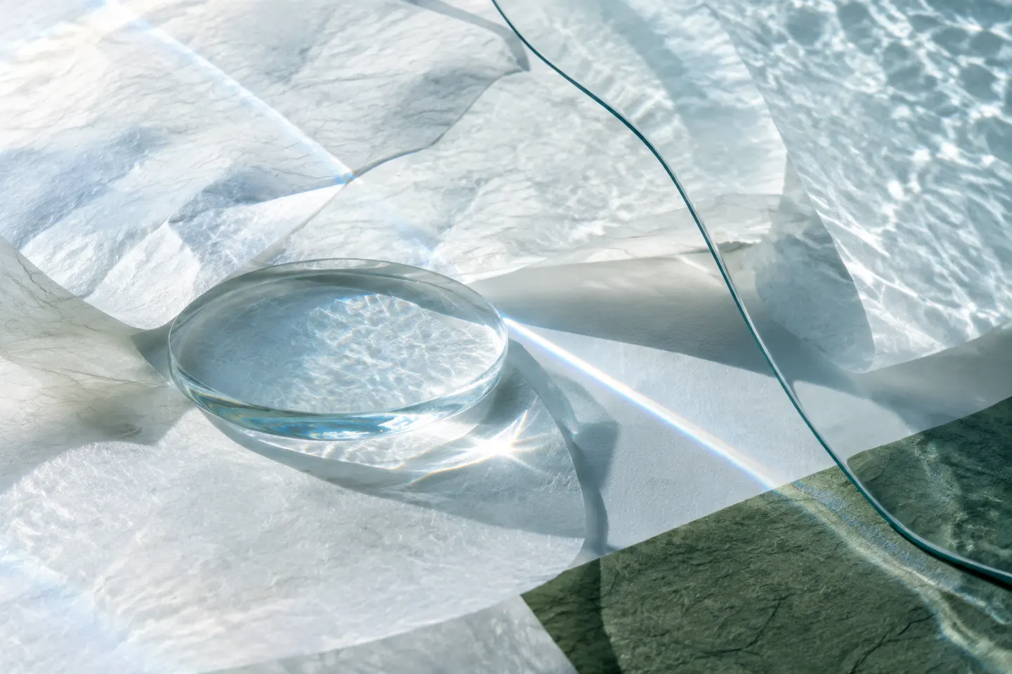 Clear water, fibrous paper and curved glass refracting daylight