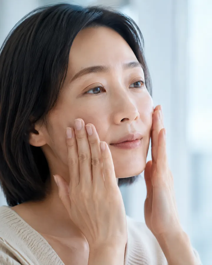 A woman gently pressing a hydrating layer into her cheeks